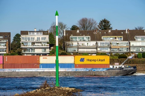 Container cargo ship on the Rhine near Düsseldorf-Bockum, villas on the banks of the Rhine, the