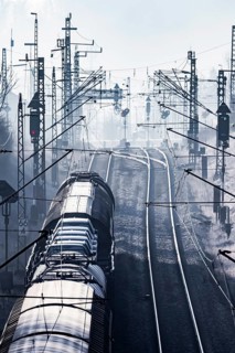 Deutsche Bahn AG tracks backlit with goods train. Overhead line, signals and infrastructure.