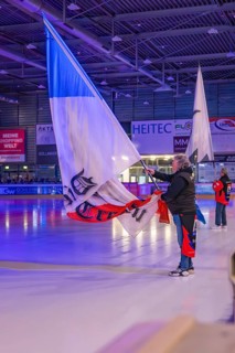 People waving large flags on an illuminated ice rink during an event, Heilbronner Falken Vs