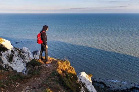 Hiker enjoying views of cliffs, chalk coast, Beachy Head, Eastbourne, South Downs, Sussex, England,