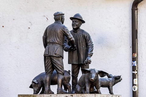Butcher and farmer haggle over the price of a pig. Statue group in memory of the Ulm mule market.