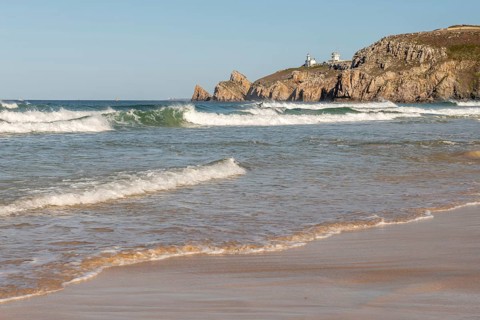 The sea is calm and the beach is sandy. The waves are small and the water is a light blue colour.