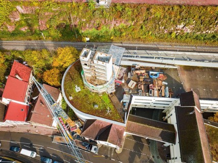 Aerial photo of a construction project with a concrete tower and surrounding streets and autumnal