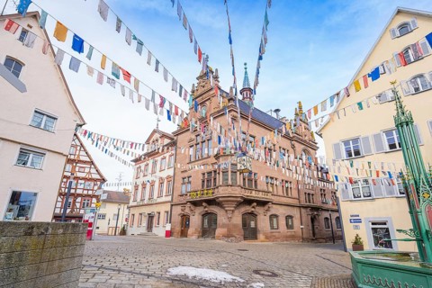 Historic building with colourful pennants and half-timbered houses on a cobbled square, Meßkirch,