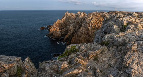 The tip of Pen Hir. The rocks are jagged and rough, the water is calm. The scenery is peaceful.