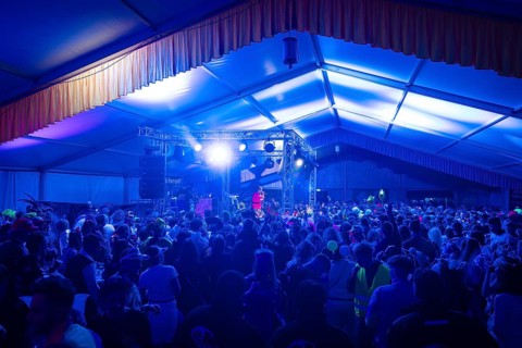 Large crowd at a night-time concert with blue stage lighting, carnival, Schlagerkuchen Donzdorf,