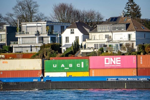 Container cargo ship on the Rhine near Düsseldorf-Bockum, villas on the banks of the Rhine, the