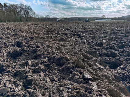 Freshly ploughed field in spring, tractor with plough in the background, Germany, Europe