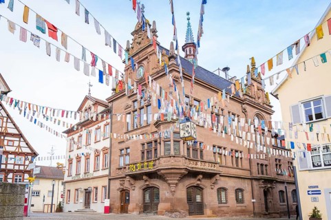 Historic building with colourful pennants and clock, surrounded by half-timbered houses, Meßkirch,