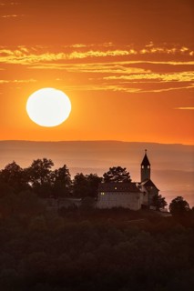Teck Castle in front of a dramatic orange sunset on a hill, near Kirchheim unter Teck, Swabian Alb,