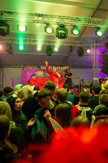 Schlager king Tobee heats up the audience in a party tent illuminated with green lights, carnival,