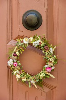 Detail of an antiquated front door with floral wreath in a building on the Krämerbrücke in the