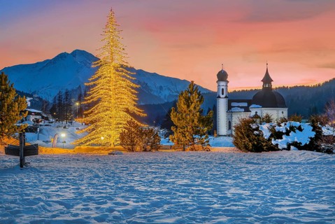 Seekirchl with artificially illuminated winter fir tree and Hocheder 2797m at dusk in winter,