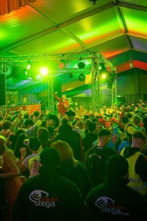 Concert atmosphere with green lights and an energetic audience in front of the stage, carnival,