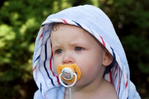 One-year-old boy with bathrobe, baby with dummy, teat