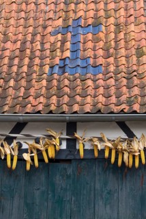 Barn with cross made of roof tiles and corn cobs
