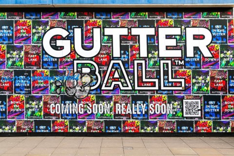 Person waking past posters on shopfront advertising Gutter Ball ten pin bowling attraction,