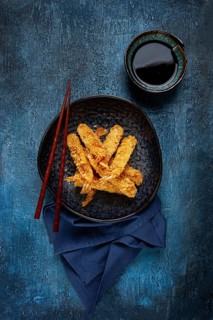 Shrimp in tempura, deep fried, on a black plate, with soy sauce, close-up, top view, no people