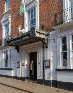 Doorman standing in entrance door of historic White Hart Hotel, Bailgate, city of Lincoln,