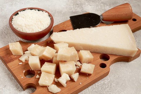 Freshly sliced and grated cheese, parmesan cheese, Gran gusto. Grana padano. on a wooden chopping