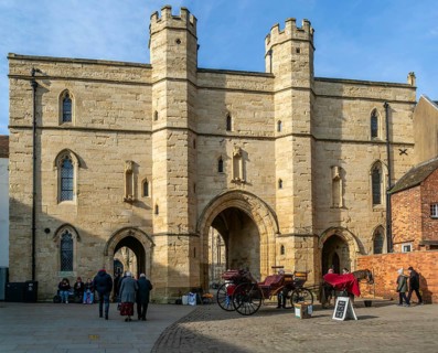Sun shining on Exchequer Gate with horse carriage rides, Minster Yard, city of Lincoln,