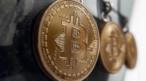 A macro shot shows a series of golden coins, each marked with a distinctive 'B' emblem. The coins,