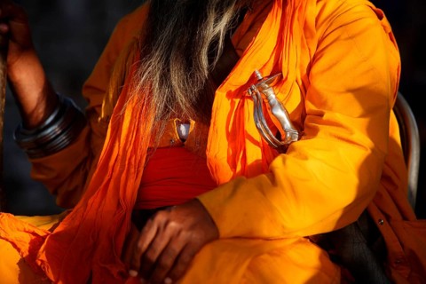 Nihang or Sikh warrior dressed up in orange robes with sword during celebrations of Hola Mohalla at