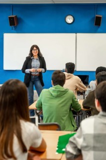 Cheerful professor is teaching a lesson to a diverse group of university students in a modern