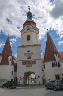 A medieval city gate with high, pointed towers under a cloudy sky, wachaus, donau, austria