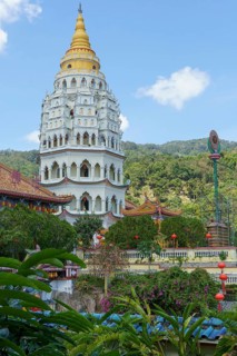 Imposing pagoda with golden spire, surrounded by green hills and blue sky, penang, malaysia