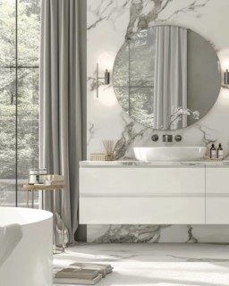 A contemporary bathroom bathed in natural light, showcasing marble walls, a round mirror, and a