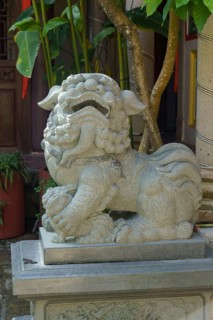 A decorative stone lion statue adorns the temple courtyard, penang, malaysia