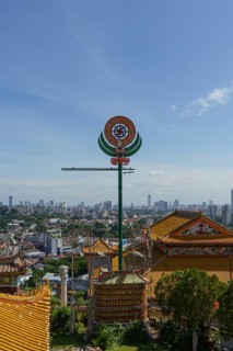A temple with detailed roof decorations and city skyline in the background, penang, malaysia