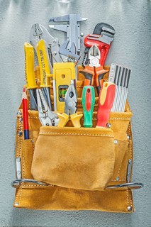 Assortment of construction tooling in tool belt on concrete background