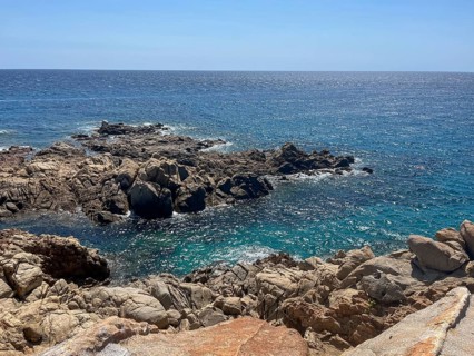 Rocky coastline with crystal clear water under a blue sky, cagliari, sardinia, italy