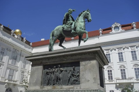 Bronze statue of a horseman on a pedestal in front of a historic building, vienna, austria
