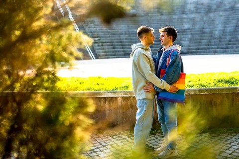 Two men embracing in a park, one showcasing a vibrant rainbow bag, celebrating lgbtq plus pride,