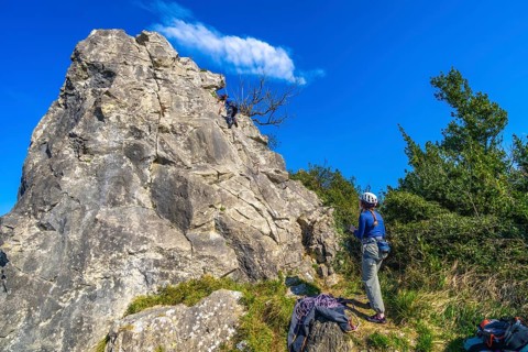 Two female rock climbers scaling a challenging cliff face, enjoying a sunny day in nature