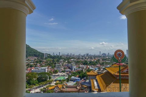 View of a city with temple buildings and modern structures under a clear sky, penang, malaysia