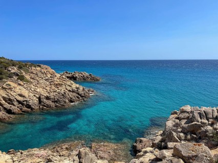 Rocky cliffs tower over the turquoise sea under a clear sky, cagliari, sardinia, italy
