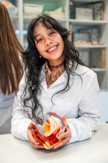 Smiling medical student holding anatomical model of female reproductive organs during anatomy class