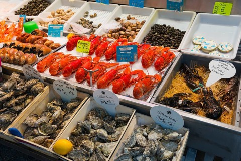 Various seafood such as lobsters and oysters on a market stall, carefully arranged, fish market,