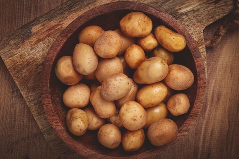 A bowl filled with freshly harvested small potatoes showcases their natural earthy tones. The