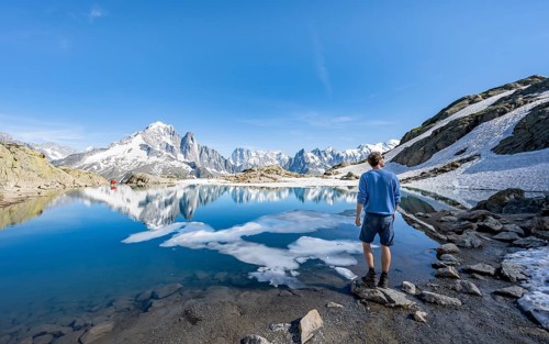 Mountaineer in front of mountain landscape with mountain lake, tourist at Lac Blanc with water