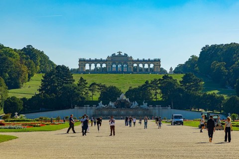 Tourists stroll in the extensive park of Schönbrunn Palace with a view of the Gloriette, Vienna,