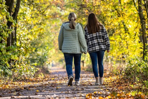 A walk through a colourful autumn forest. Two young woman on a circular path on the banks of the
