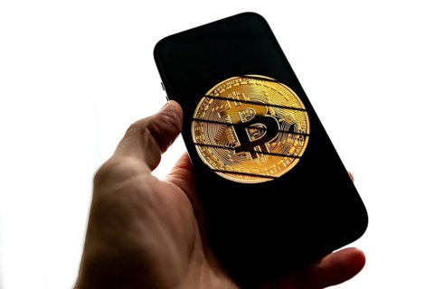 Smartphone held by hand, symbol image cryptocurrency, digital currency, golden coin Bitcoin,