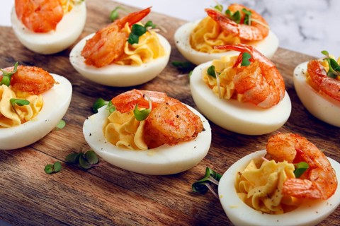 Boiled eggs stuffed with yolk and seasoned with mayonnaise, stuffed eggs with shrimp, on a wooden