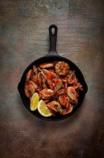 Fried shrimps, in a cast-iron pan, shrimps for beer, in a newspaper, on a gray table, there are no