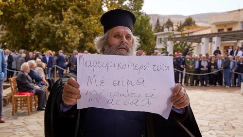 Priest shows a sign during a meeting in front of a building, Visit of the Federal President